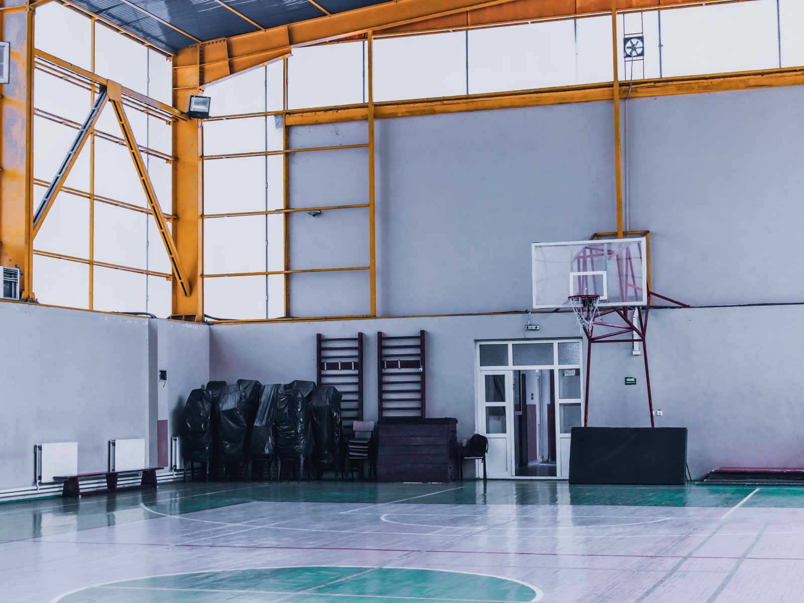 Empty indoor sports hall with a basketball hoop and a steel frame